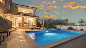 Ein Pool mit Terrassenbereich, einer überdachten Sitzgelegenheit im Freien und einem Gebäude mit Steinverkleidung.