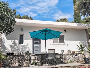 A patio with a table and chairs, a teal umbrella, and potted plants. - mit riesigem Garten by Interhome (Trogir/Seget Donji)