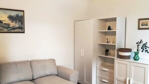 En stue med en sofa, et klædeskab og et skab med hylder.