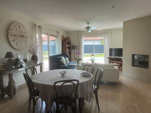 Ein Essbereich mit einem runden Tisch, Stühlen, einer Uhr und einem Fernseher im Hintergrund.