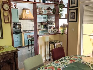 A kitchen with a bar area, a dining table with chairs, and a clock on the wall. - Große Ferienwohnung in Ližnjan mit Offenem Kamin by Interhome (Medulin/Ližnjan)