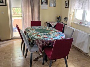 A dining area with a table covered in a floral tablecloth, surrounded by four chairs. - Große Ferienwohnung in Ližnjan mit Offenem Kamin by Interhome (Medulin/Ližnjan)
