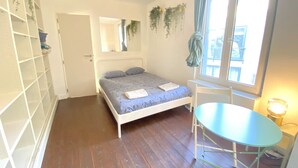 Ein Schlafzimmer mit Bett, Schreibtisch, Stuhl, Fenster und Tür.