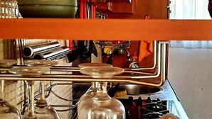A kitchen with wooden cabinets, a plant, a wine glass, and a bread loaf. - Geräumiges Ferienhaus mit kleinem Garten, nur fünf Gehminuten vom bekannten Bas by Interhome (Sarajevo)