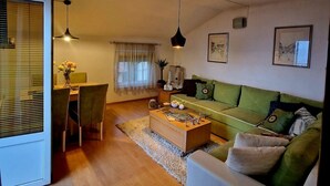 A living room with a sofa, coffee table, and a dining area with a table and chairs. - Geräumiges Ferienhaus mit kleinem Garten, nur fünf Gehminuten vom bekannten Bas by Interhome (Sarajevo)