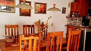A wooden dining table with chairs, a vase with flowers, and hanging pendant lights. - Geräumiges Ferienhaus mit kleinem Garten, nur fünf Gehminuten vom bekannten Bas by Interhome (Sarajevo)