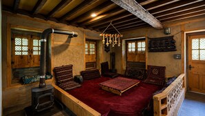 Una habitación tradicional con una cama grande, muebles de madera, una chimenea y vistas a través de una ventana con diseño de celosía.
