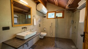 Un baño con un espejo grande, un lavamanos, un inodoro y una ducha con mampara de vidrio.