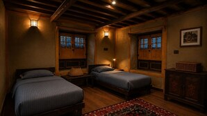 Una habitación con dos camas, una mesita de noche, una lámpara, un armario y una alfombra.
