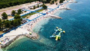 Oversigtsbillede af et kystområde med strand, parkeringsplads og en bro med både.