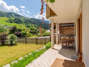 Une terrasse avec une table et des chaises, une clôture en bois et une vue sur des collines verdoyantes.