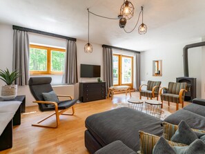 A modern living room with a sofa, armchairs, a TV, and a fireplace. - Comfortable apartment opposite Skilift (Maria Alm)