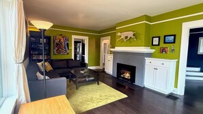 Ein Wohnzimmer mit Kamin, einer Couch, einem Couchtisch und einem Bücherregal.