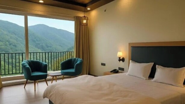 Une chambre d’hôtel avec un lit, deux chaises, une table de chevet et une vue sur les montagnes.