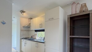 Pieni, käytännöllinen keittiö, jossa on valkoiset kaapit, kaasuliesi ja ikkuna.
