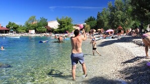 A beach with clear water, people swimming and sunbathing, and a boat in the water. - Sonnige Wohnung in Bibinje mit privatem Parkplatz by Interhome (Zadar/Bibinje)