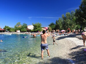 A beach with clear water, people swimming and sunbathing, and a boat in the water. - Sonnige Wohnung in Bibinje mit privatem Parkplatz by Interhome (Zadar/Bibinje)