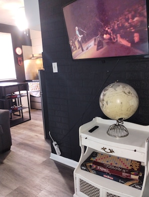 Ein Zimmer mit Fernseher, der ein Konzert zeigt, einem Globus auf einem Regal und einem Monopoly-Spiel.