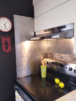 Eine Küche mit einem Edelstahlherd, einer Uhr und einem dekorativen Schild an der Wand.