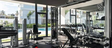 A modern gym with various exercise equipment, a bench, and a rack of dumbbells.