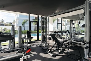 A modern gym with various exercise equipment, a bench, and a rack of dumbbells. - 2BR/2.5BA Beachfront Condo | Sol de Arena B2 (Las Terrenas)