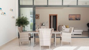 A modern living room with a dining area, featuring wicker furniture, a potted plant, and artwork on the walls. - 2BR/2.5BA Beachfront Condo | Sol de Arena B2 (Las Terrenas)
