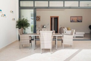 A modern living room with a dining area, featuring wicker furniture, a potted plant, and artwork on the walls. - 2BR/2.5BA Beachfront Condo | Sol de Arena B2 (Las Terrenas)