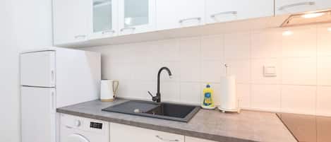 Een koelkast, een microgolfoven, een oven, kookgerei, borden en bestek