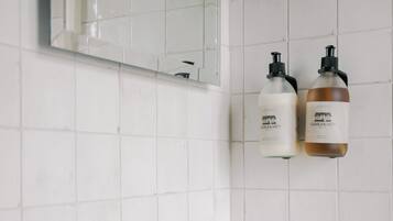 A bathroom with a white sink, gold faucet, and two bottles of lotion on the wall.