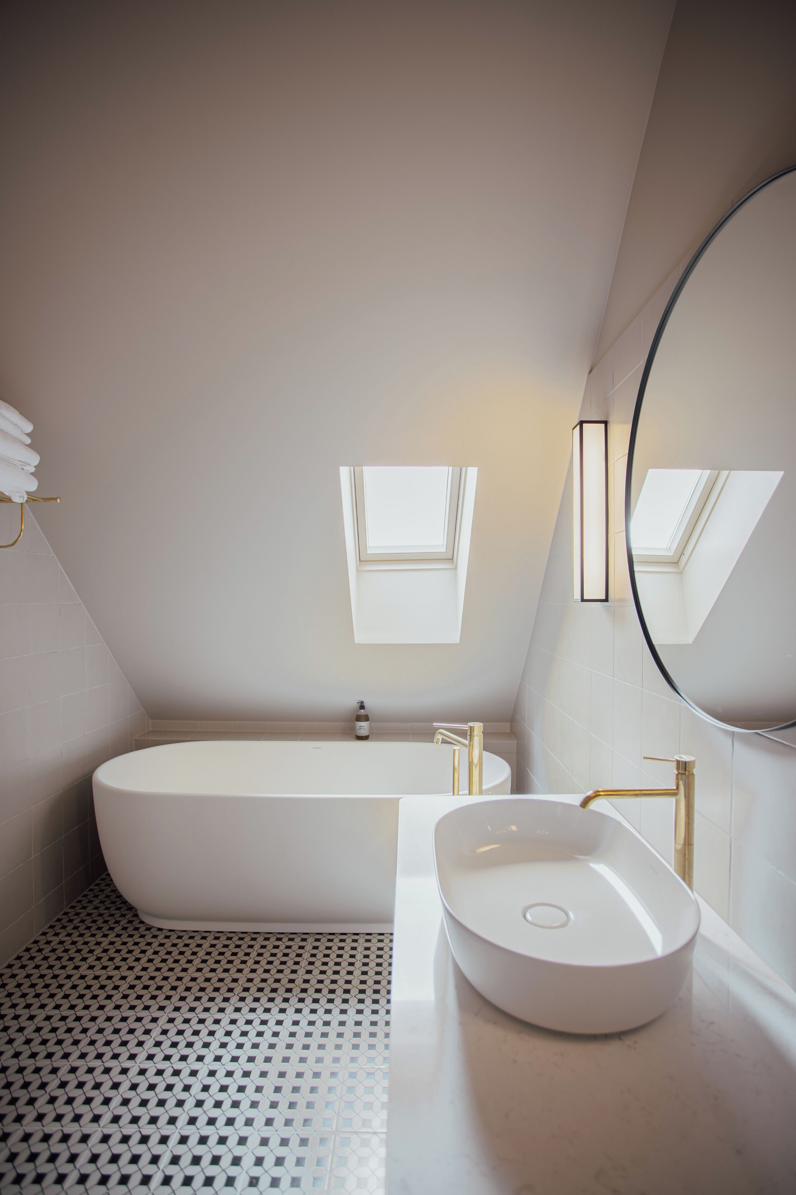 Un baño moderno con una bañera independiente, un lavabo sobre encimera y un espejo grande.