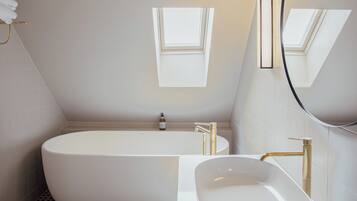 Un baño moderno con una bañera independiente, un lavabo sobre encimera y un espejo grande.