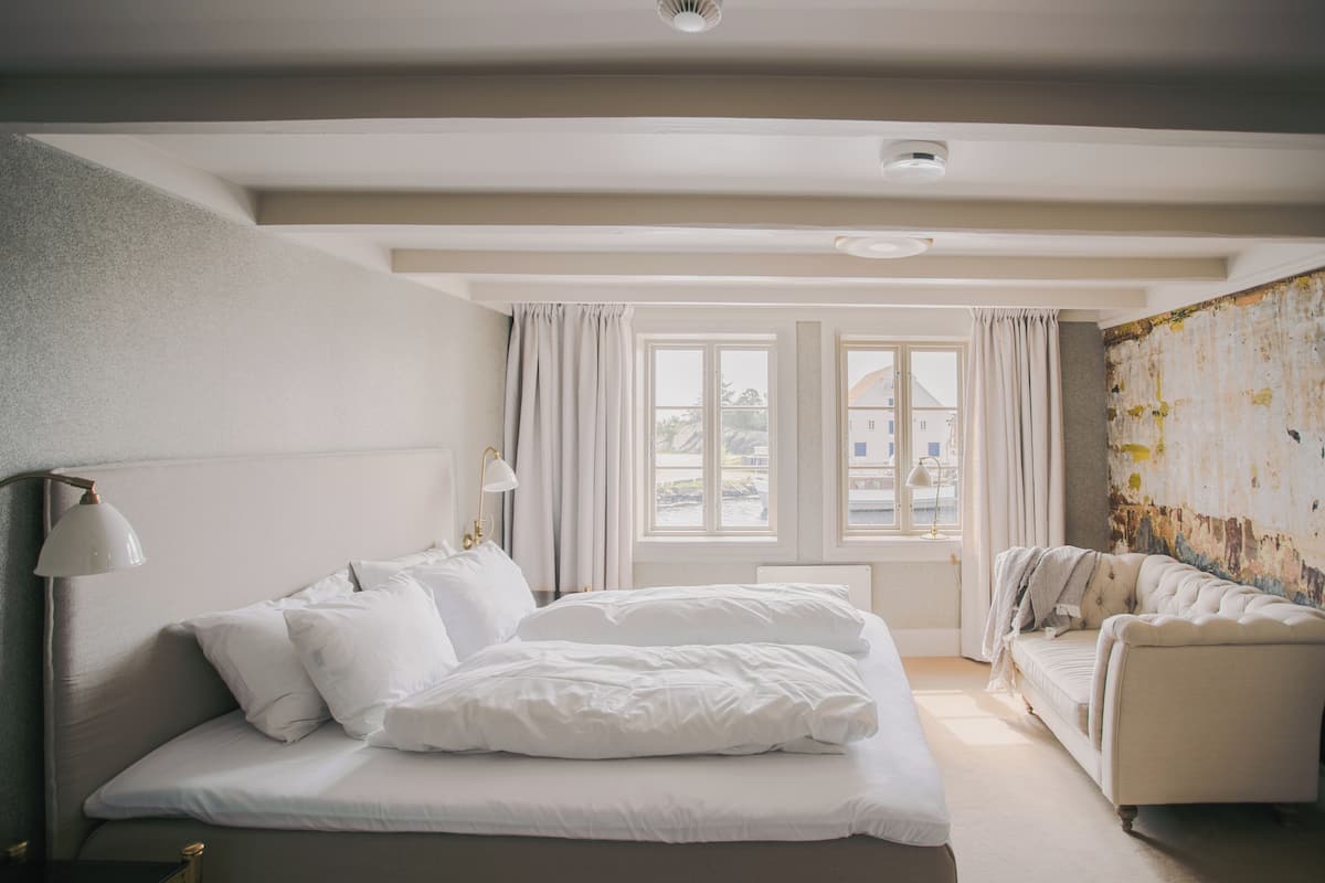 Een slaapkamer met een bed, een bedlamp, een bank en een raam met gordijnen.