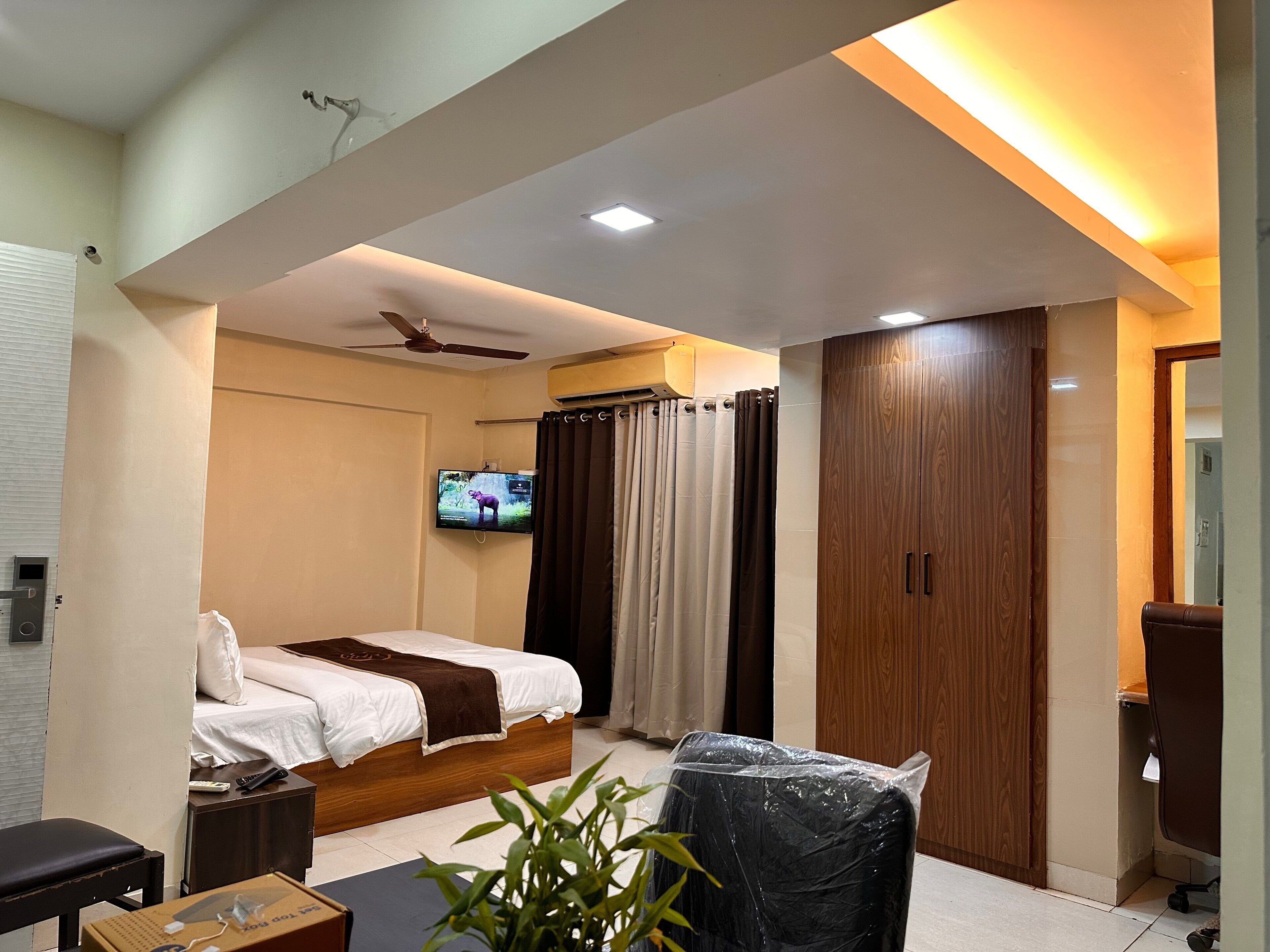 A modern bedroom with a bed, a TV, a ceiling fan, and a wardrobe.