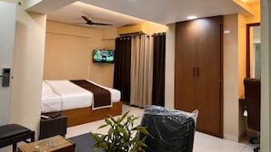 A modern hotel room with a bed, a TV, a ceiling fan, and a large wardrobe.