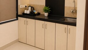 A modern kitchen with wooden cabinets, a black countertop, a stainless steel sink, and a potted plant.