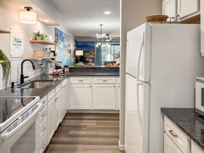 Eine moderne Küche mit weißen Schränken, einer Granit Arbeitsplatte und einem eingebauten Kühlschrank.