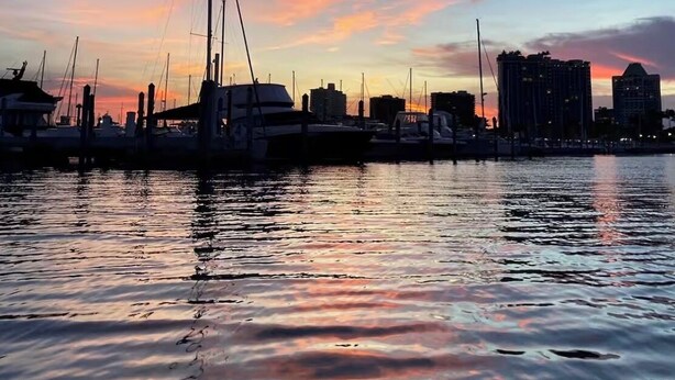 A marina with boats docked, a city skyline in the background, and calm water reflecting the sky. - My Time Boat House, Coconut Grove Miami (Miami)