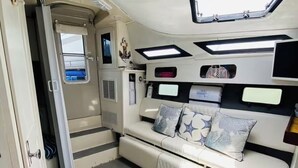 A cozy RV interior with a sofa, pillows, a small window, and overhead lighting. - My Time Boat House, Coconut Grove Miami (Miami)