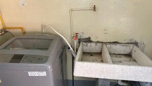 Un'area lavanderia con lavatrice, lavandino e cestino.