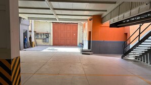 Ambiente interno con pavimento in cemento, una scala e un'ampia porta in legno.