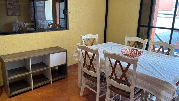 Un'area pranzo con tavolo e sedie, una panca e una finestra con tende.