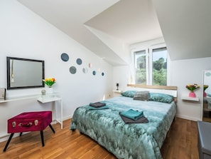 Ein Schlafzimmer mit Bett, Schreibtisch, Stuhl und Fenster.