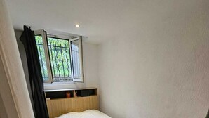 Een slaapkamer met een bed, een raam en een deur.
