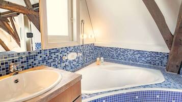 A bathroom with a bathtub, a sink, and blue mosaic tiles.