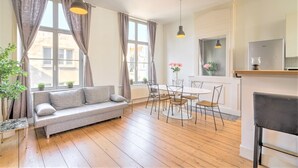 Un salon moderne comprenant un canapé, une table à manger, des chaises et un coin cuisine avec un réfrigérateur.