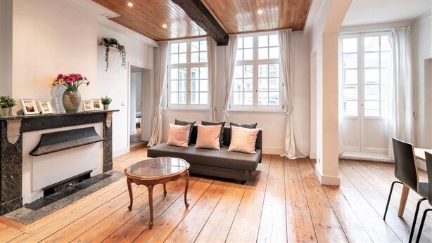 Un salon avec une cheminée, un canapé et de grandes fenêtres.