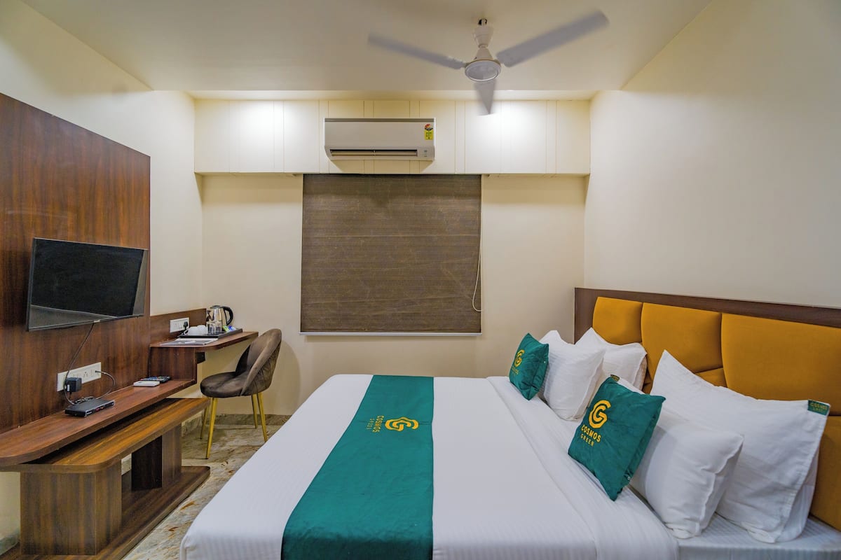 Une chambre d’hôtel équipée d’un lit, d’un bureau, d’une chaise, d’une télévision, d’un climatiseur et d’un ventilateur de plafond.