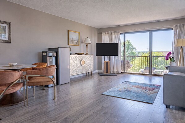 Una sala de estar moderna con comedor, un televisor de pantalla plana y un balcón con vistas.