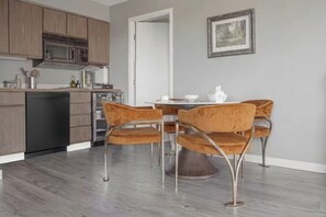Una cocina moderna con armarios de madera, microondas integrado y un comedor con una mesa redonda y cuatro sillas.