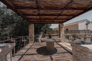 An outdoor patio area with a stone table, a pergola overhead, and a stone wall. - Guince House by All About Paxos (Paxos)